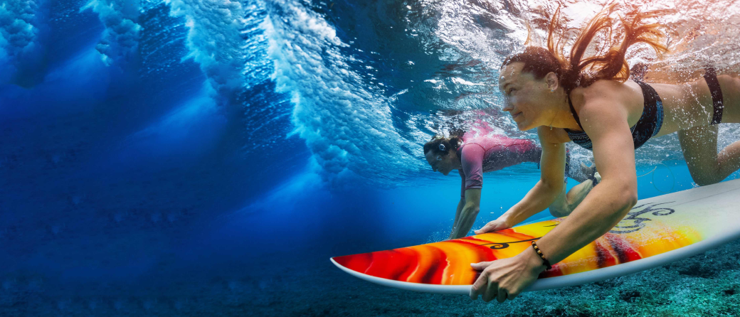 two people swimming underwater with their surfboards