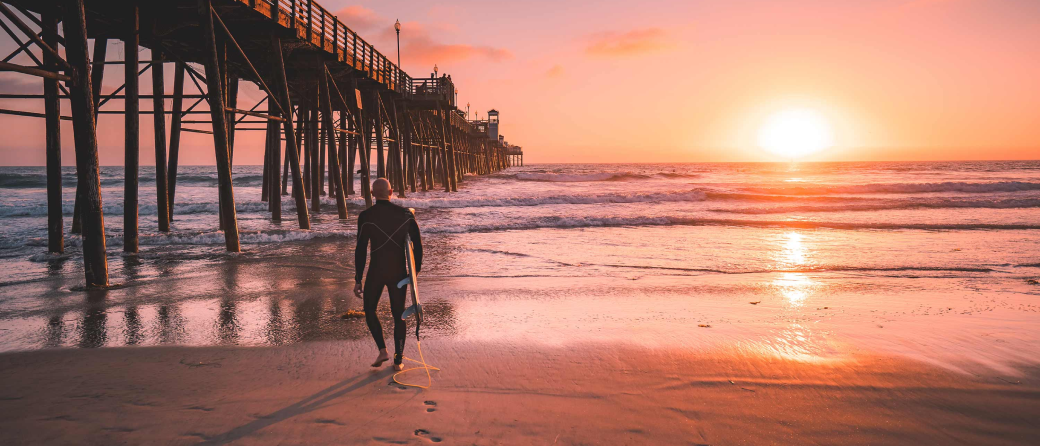 A surfer walking up the beach in Southern California
