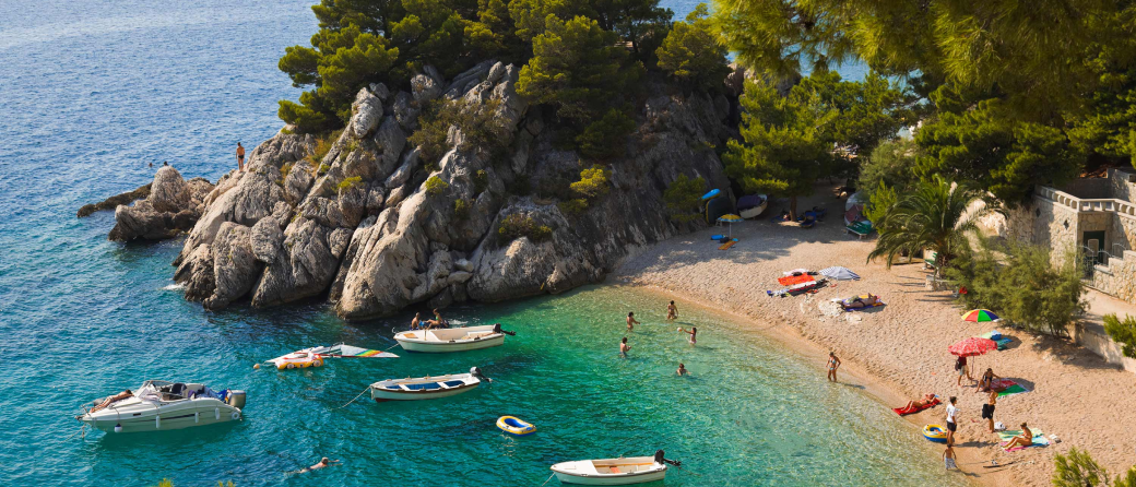 Aerial shot of a cove with boats and people lounging on the beach