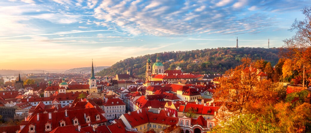 Aerial view of Prague, Czech Republic in the Fall. Trees with orange colored leafs hover in the foreground.