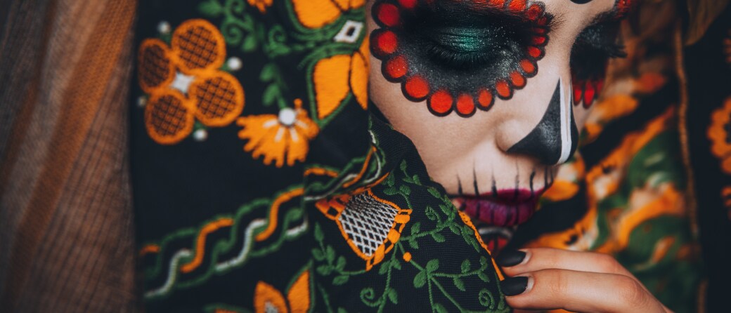 Close-up shot of a woman wearing Day of the Dead face paint and a festive costume.
