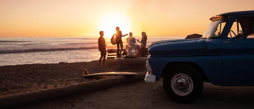 A group of friends camping on a San Diego, California beach at sunset.