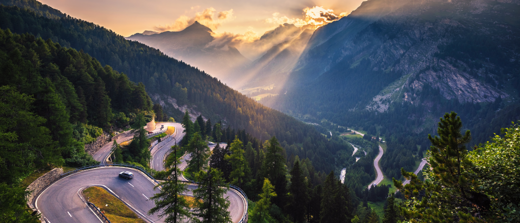 A car is making its way up a winding road to the top of a Swiss mountain.