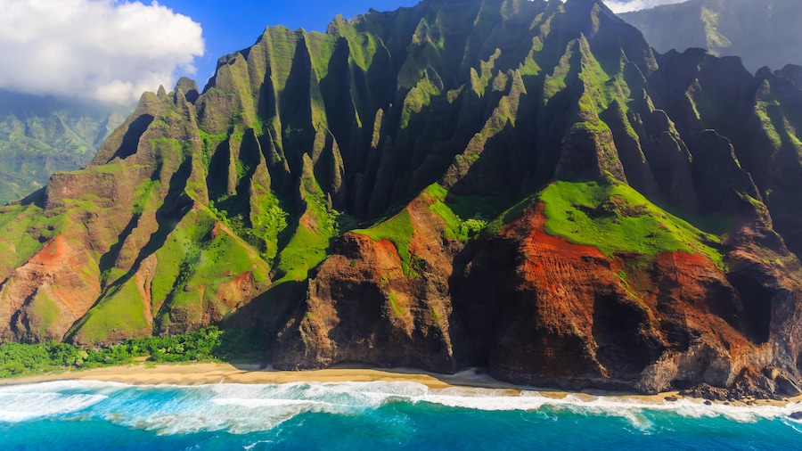 green and red mountains next to the sea in hawaii
