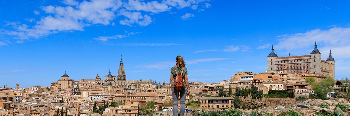 A couple of girls laughing and riding a bike along the sunny beach in a new city.