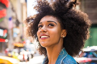 A woman smiles as she walks a city street.