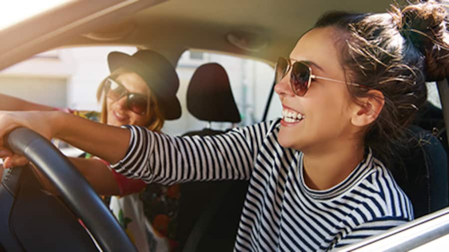 Two friends wearing sunglasses in their rental car.