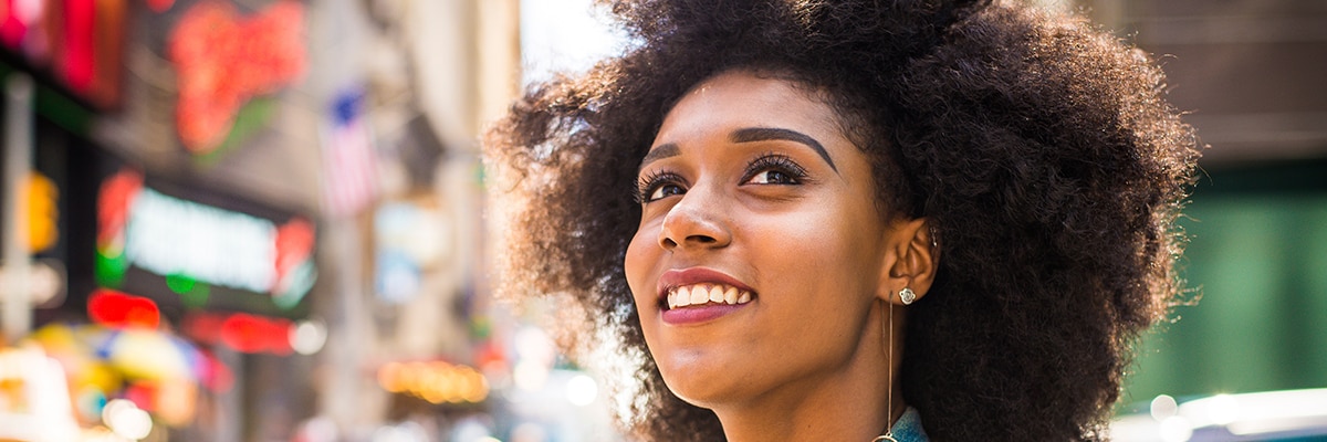 A woman smiles as she walks a city street.
