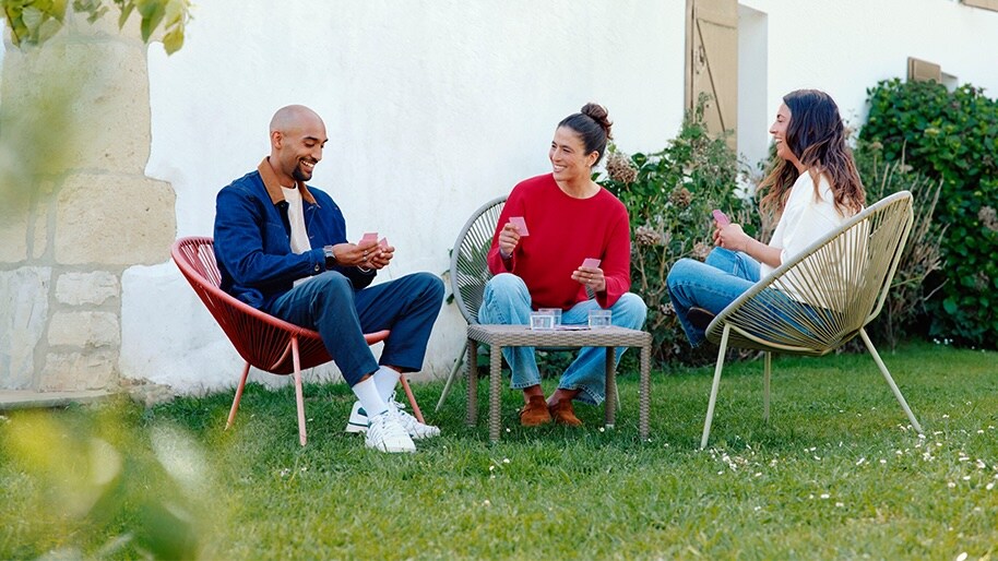 Three friends playing cards in a garden.