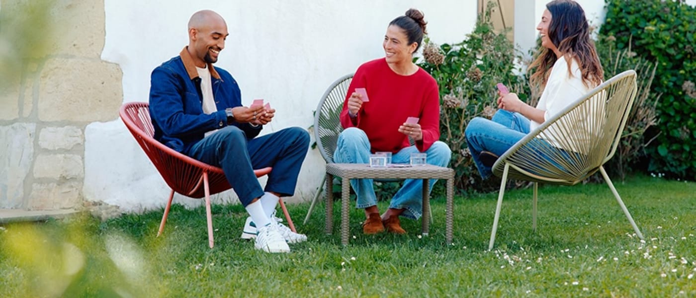 Three friends playing cards in a garden.