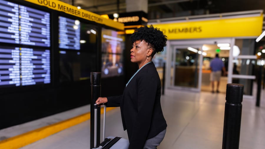 A woman looks at the Hertz car rental board.