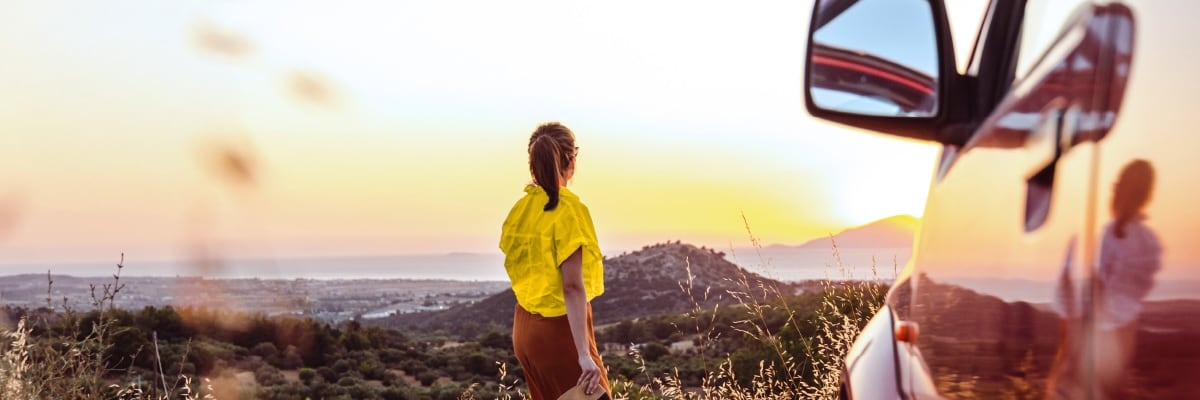 A woman looking at out a Sunset. Hertz Car Rentals.