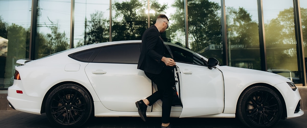 A man gets in the passenger side door of a car.