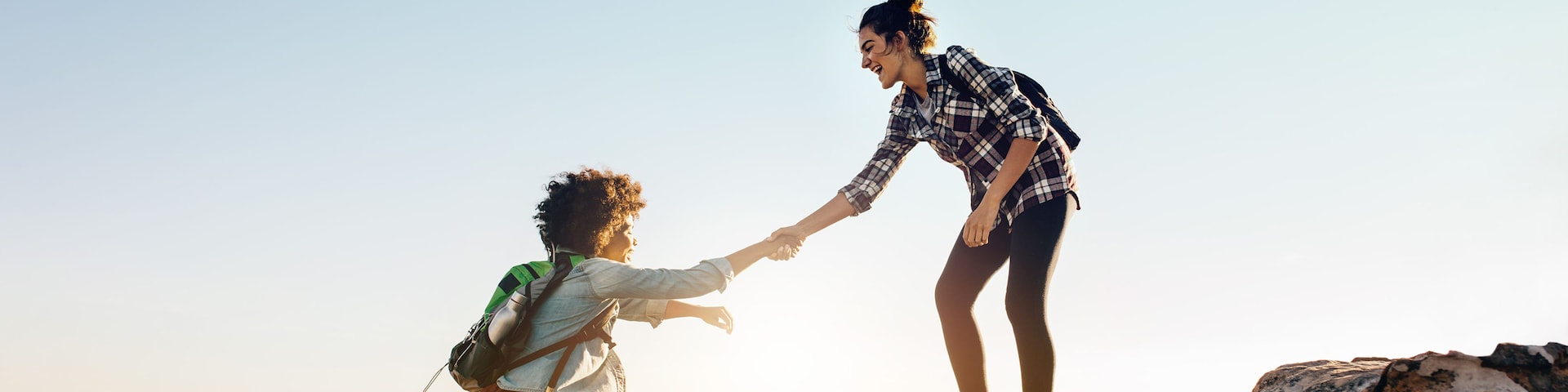 A lady helping other woman to climb a mountain - Contact Vrbo