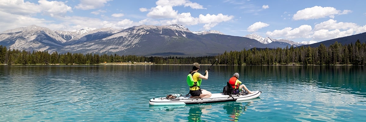 Two people paddle board on scenic Annette Lake in Jasper National Park.