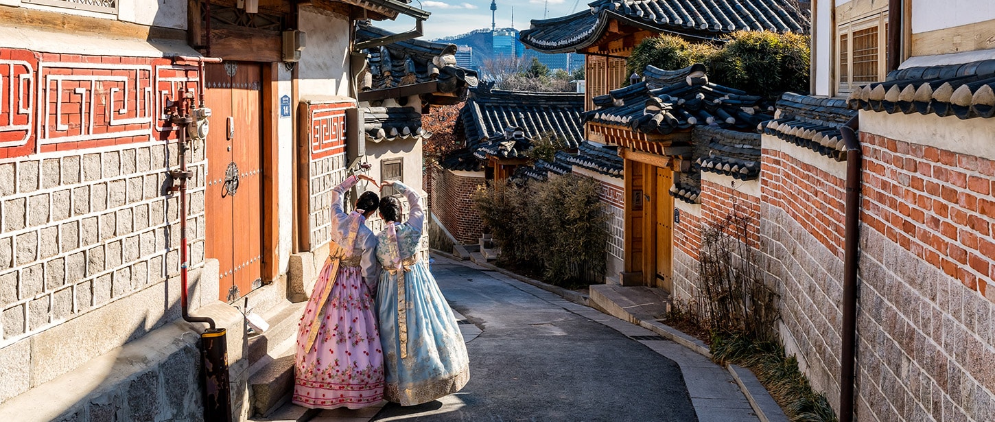 Two women in dresses walking down a street