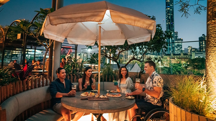 A group of people sitting at a table under an umbrella