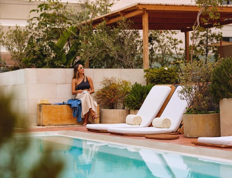 A woman in sunglasses enjoys relaxing poolside.