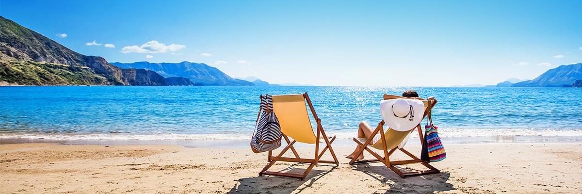 Two deckchairs on a sandy beach