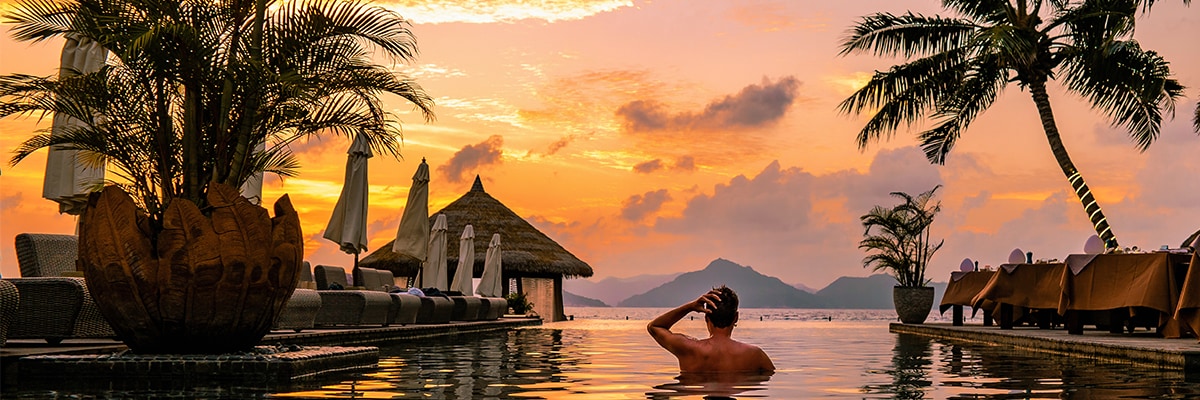 A man in the water in sunset with palm trees