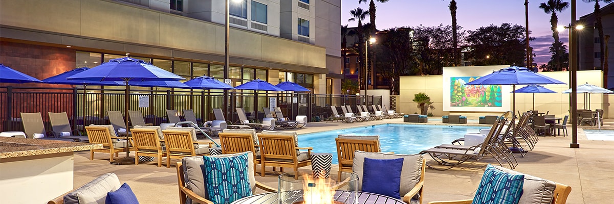 Hotel pool area with outdoor seating surrounding small fire