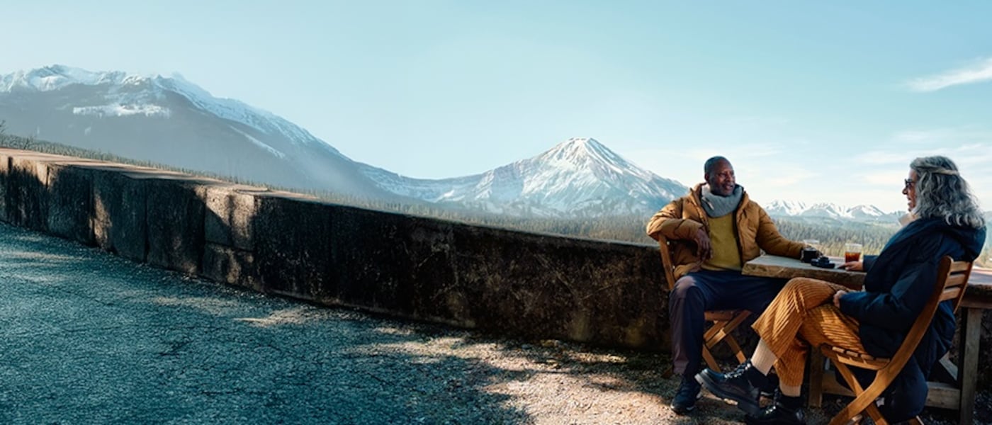 A couple sitting in front of a scenic mountain range.