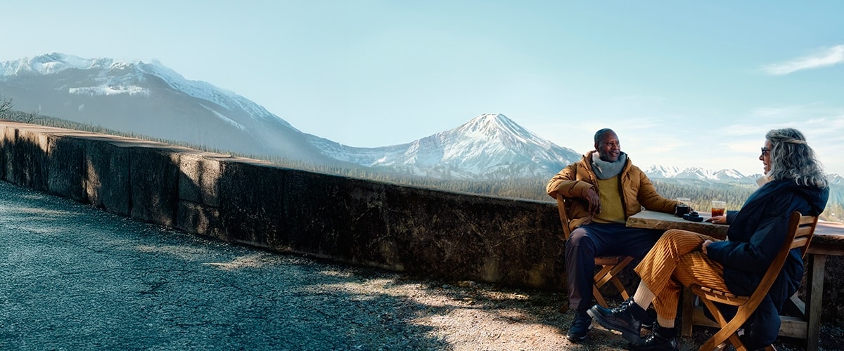 A couple sitting in front of a scenic mountain range.