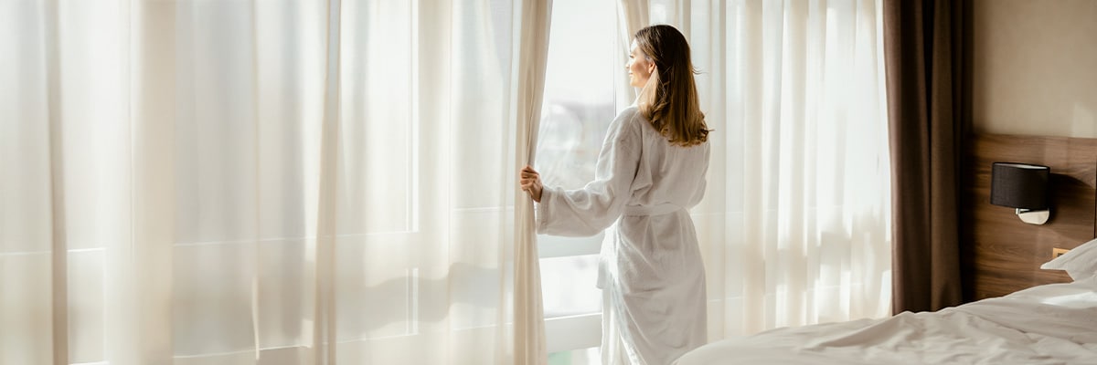 Woman looking outside hotel room window
