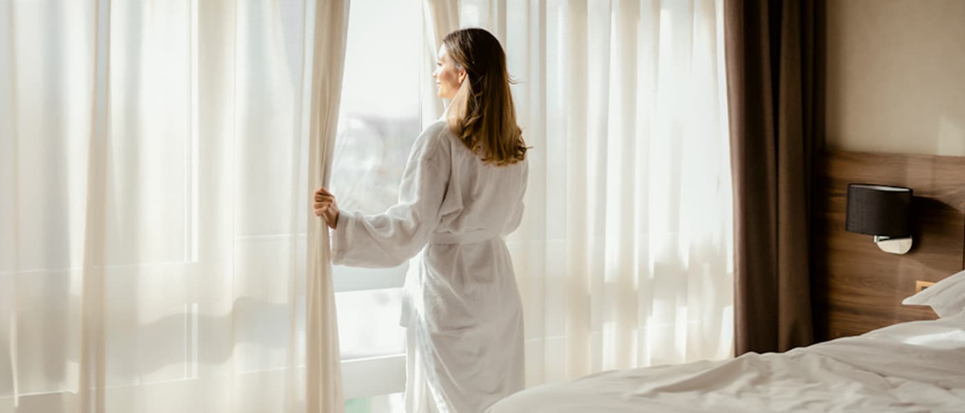 Woman looking outside hotel room window