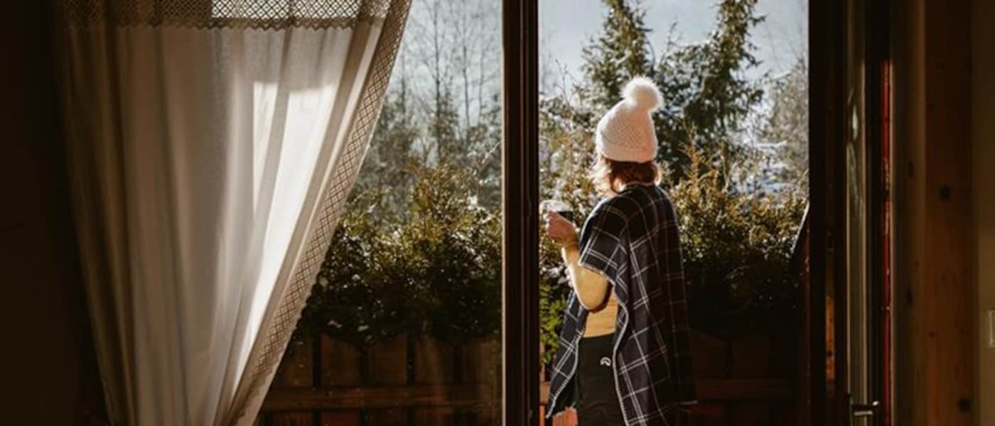 Woman enjoying hot cup tea looking at snowy mountains.
