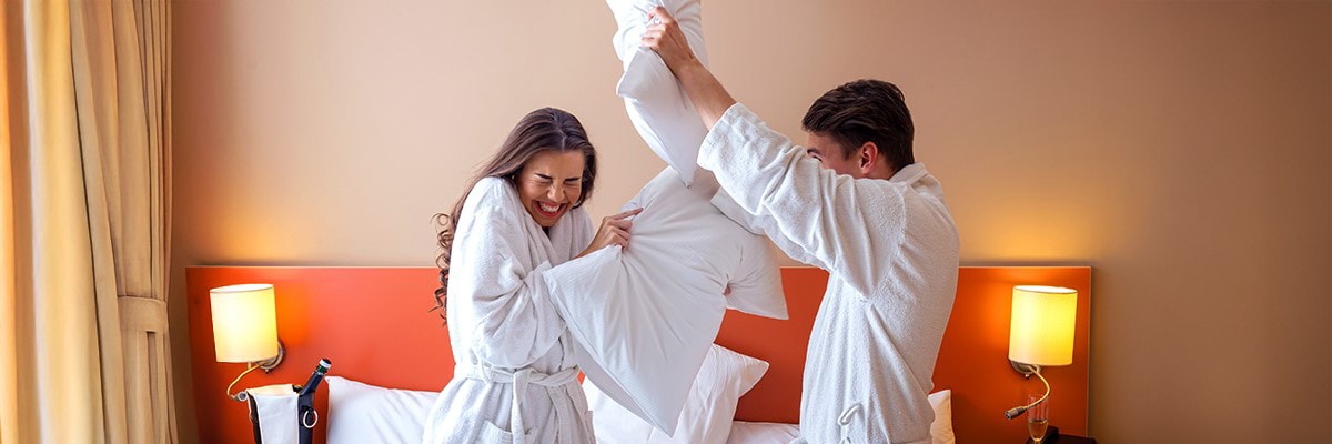 Couple having a pillow fight in hotel room