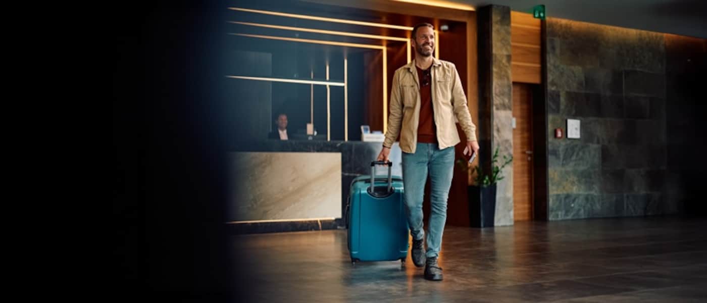 A man walks through a hotel lobby with his roller luggage.