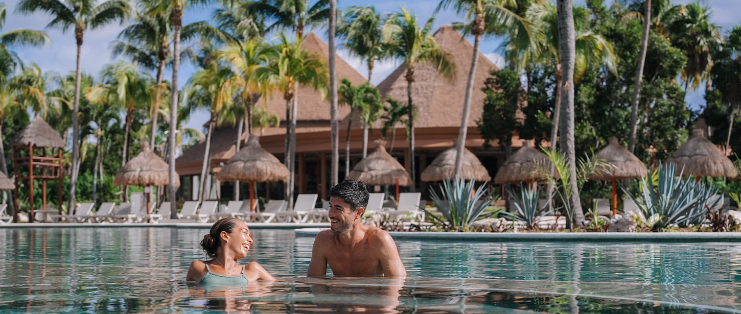 People in a swimming pool at a tropical resort.
