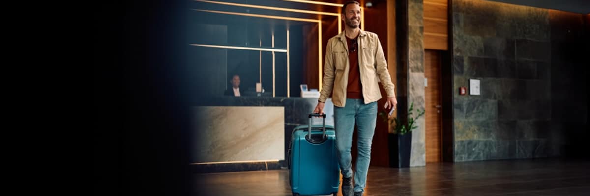 A man walks through a hotel lobby with his roller luggage.