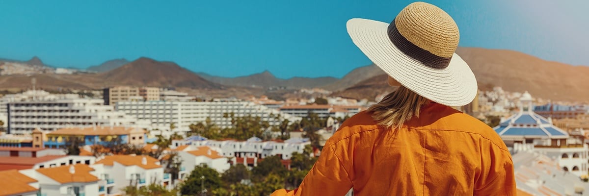 A woman looks over a resort town from a balcony.