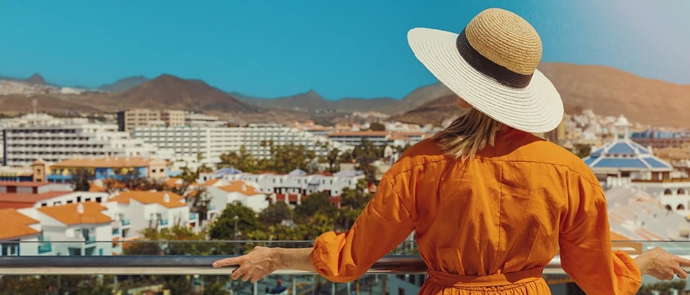 A woman looks over a resort town from a balcony.