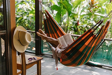 Someone lying on a hammock reading a book