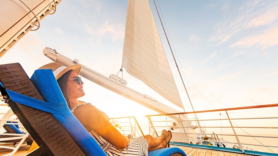 A woman sits in the sun on a cruise deck.