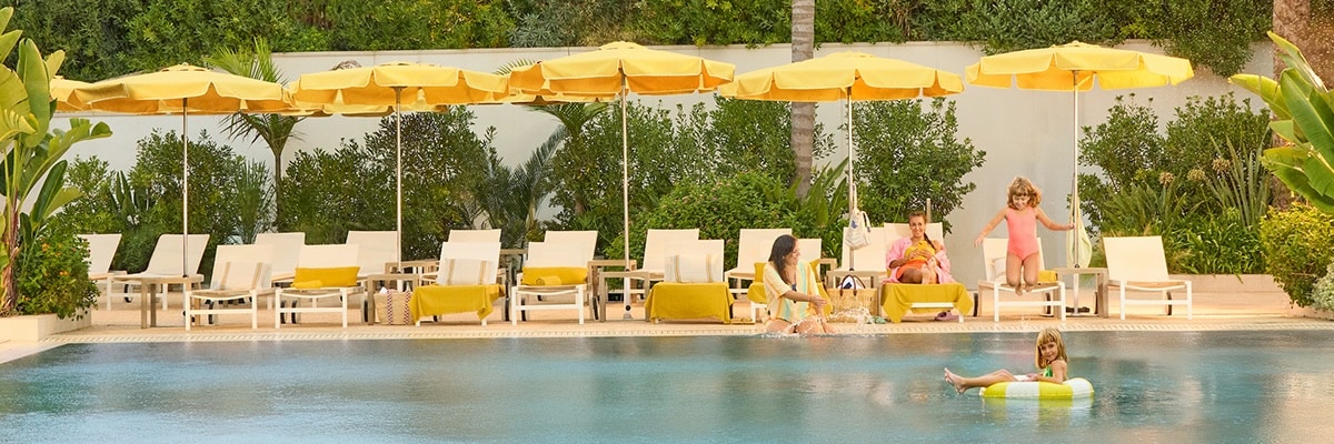 A family at the pool with yellow sun umbrellas.