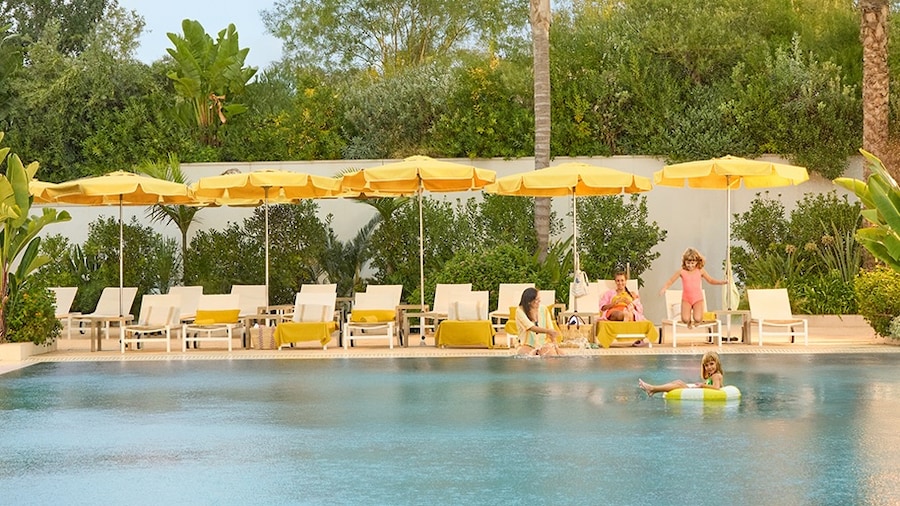 A family at the pool with yellow sun umbrellas.