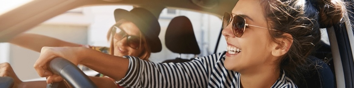Two friends wearing sunglasses in their rental car.