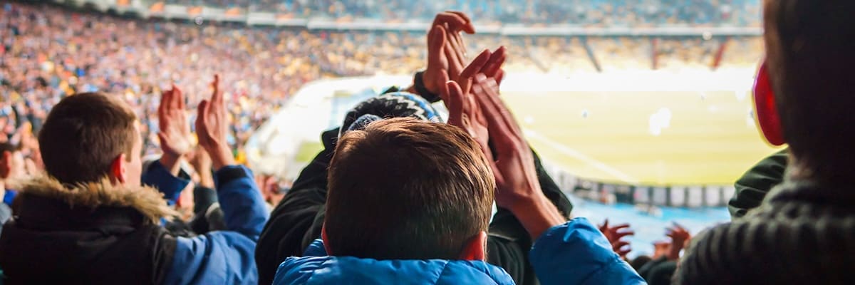 Fans enjoy a soccer match under the lights.