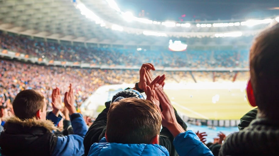 Fans enjoy a soccer match under the lights.