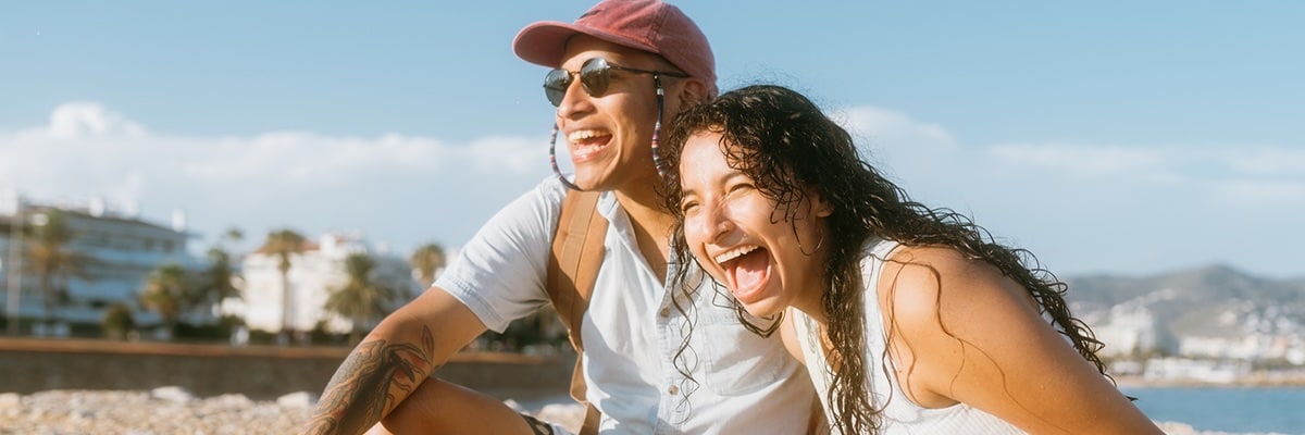 A couple laughs together on a beach.