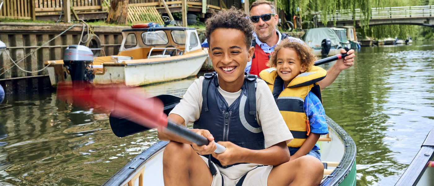 Boy and girl with a man on a river canoe wearing life vests.