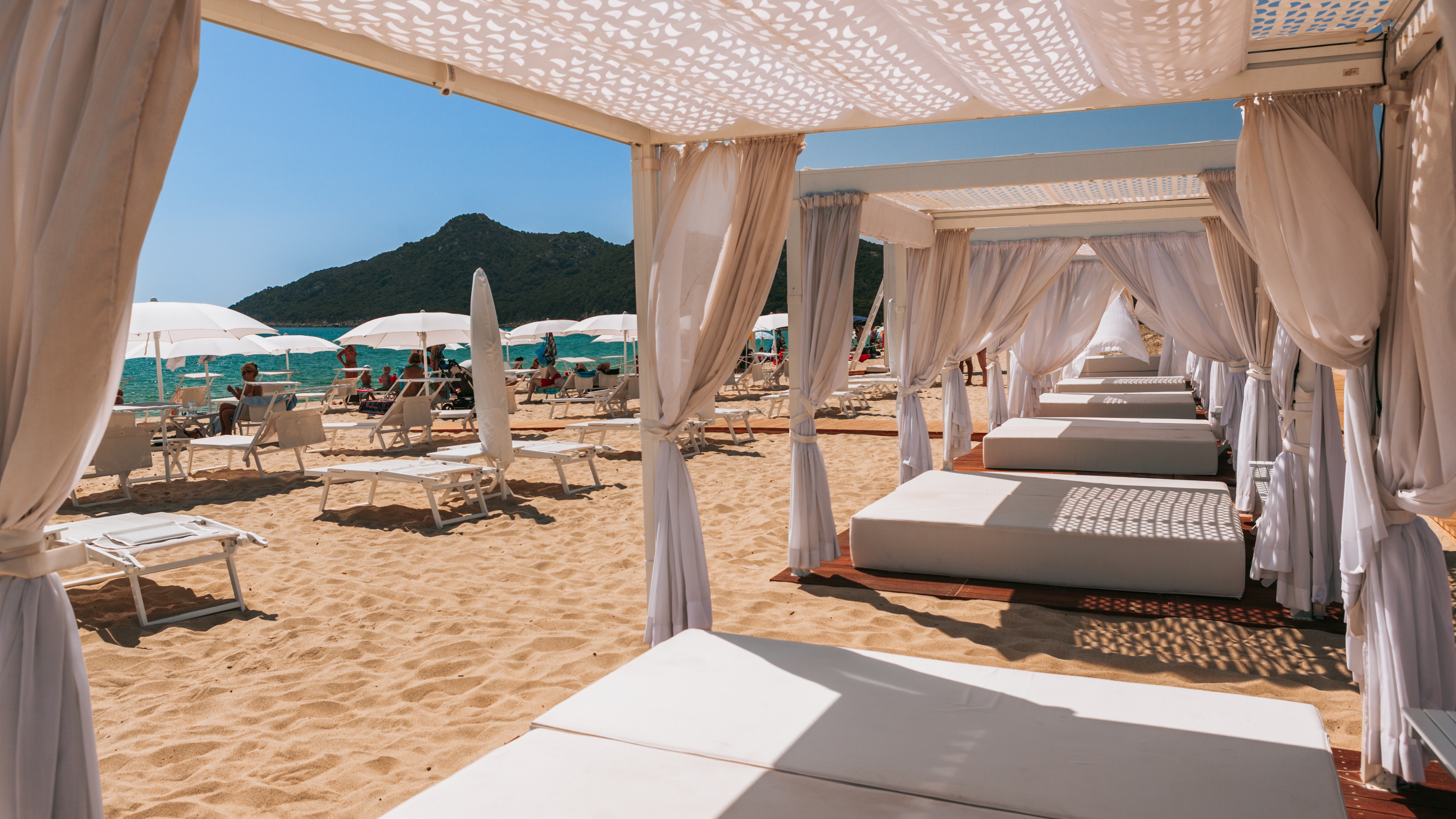 Beach cabanas lined up along the shore with a calm ocean and resort-like atmosphere