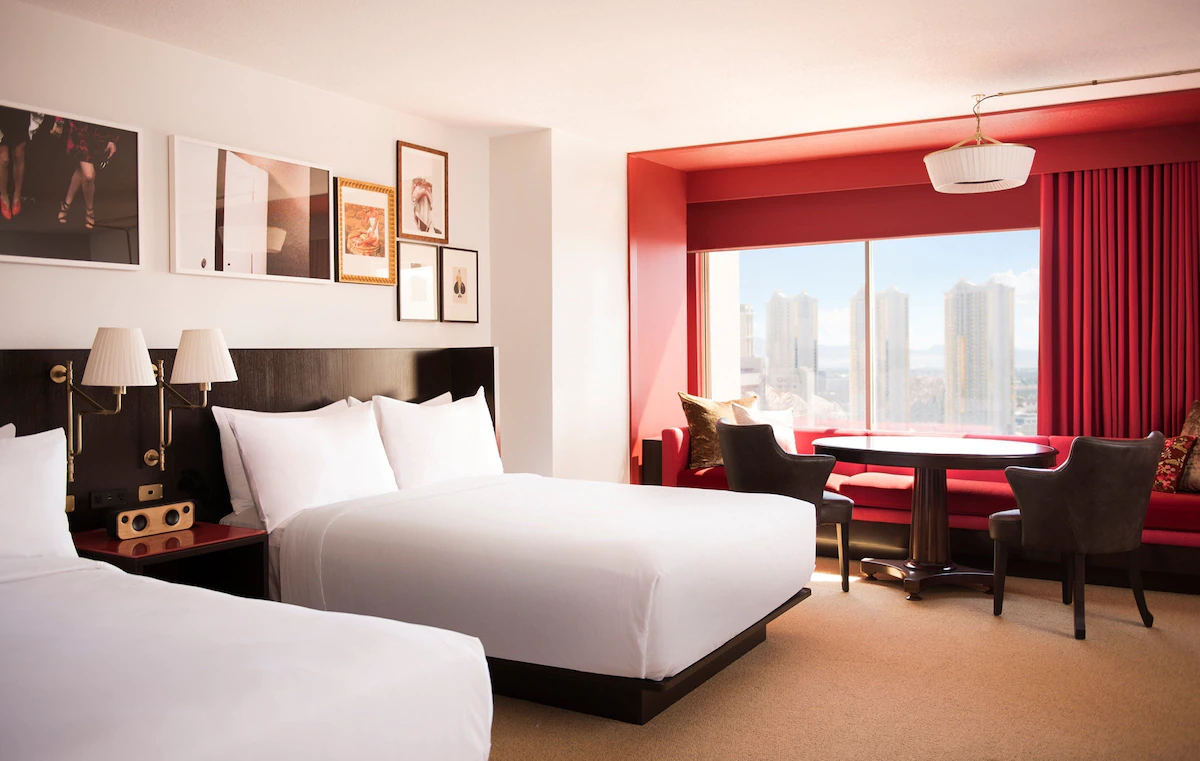 Chambre d’hôtel au Park MGM Las Vegas avec des draps d’un blanc immaculé et des touches de rouge vif sur un mur.